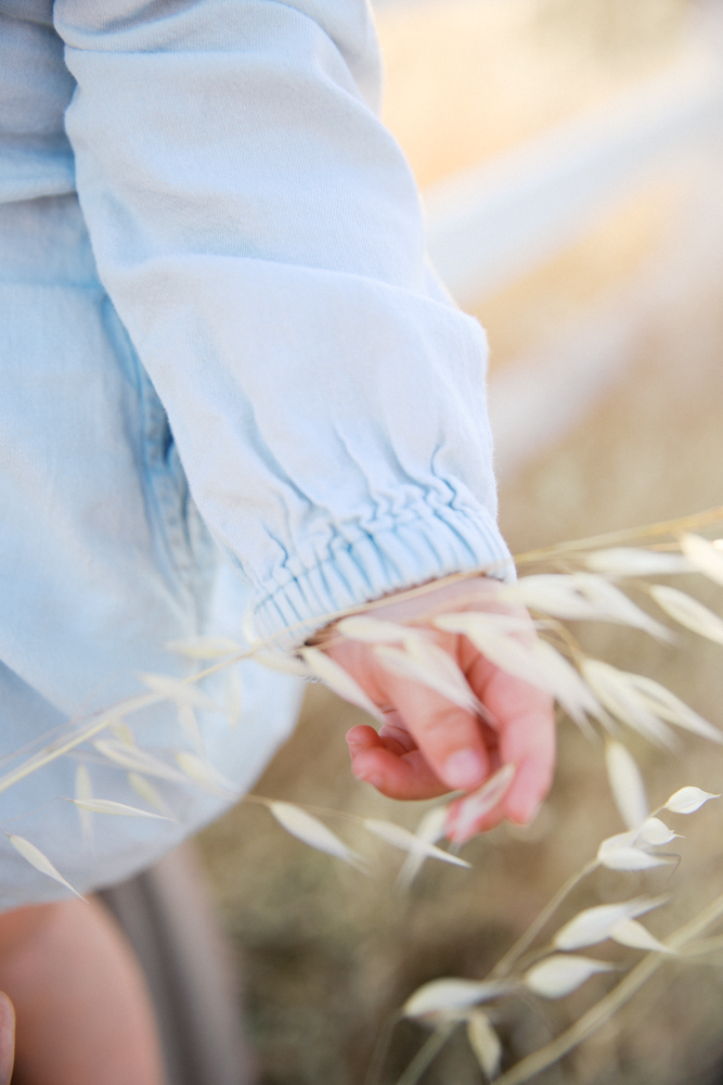 Woman walking with her child through a golden field at sunset, one of the best locations for family photos in Sacramento