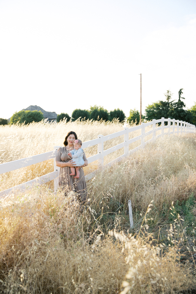Parent and child holding hands while walking through a golden field in Sacramento