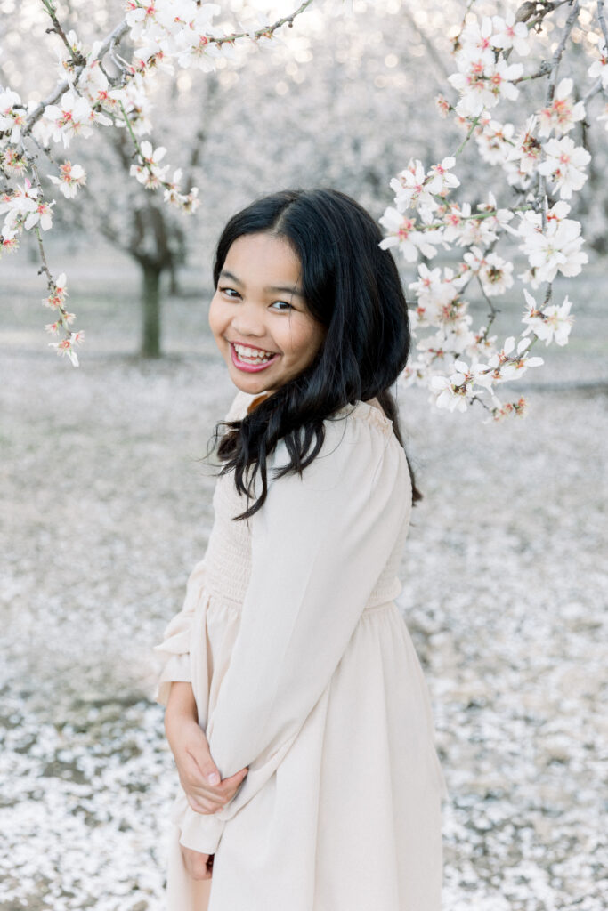 Woman smiling among white almond blossom trees near Dixon, California