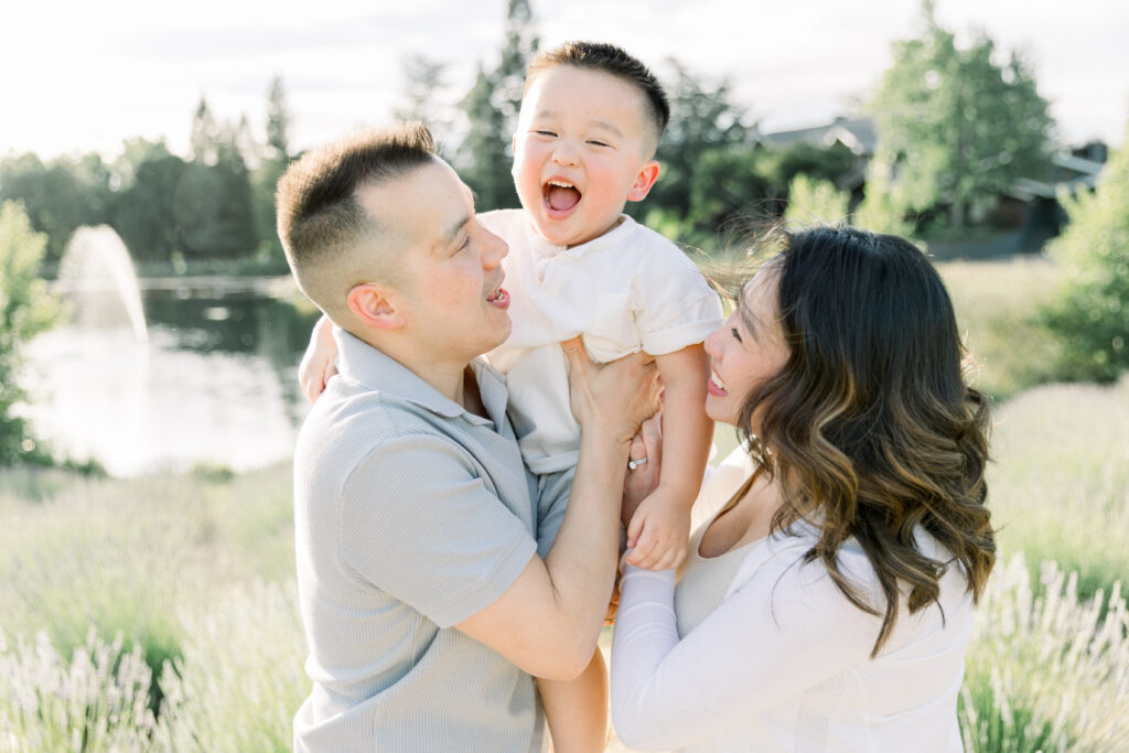 boy smiling as dad and mom hold him at lavender farm near sacramento