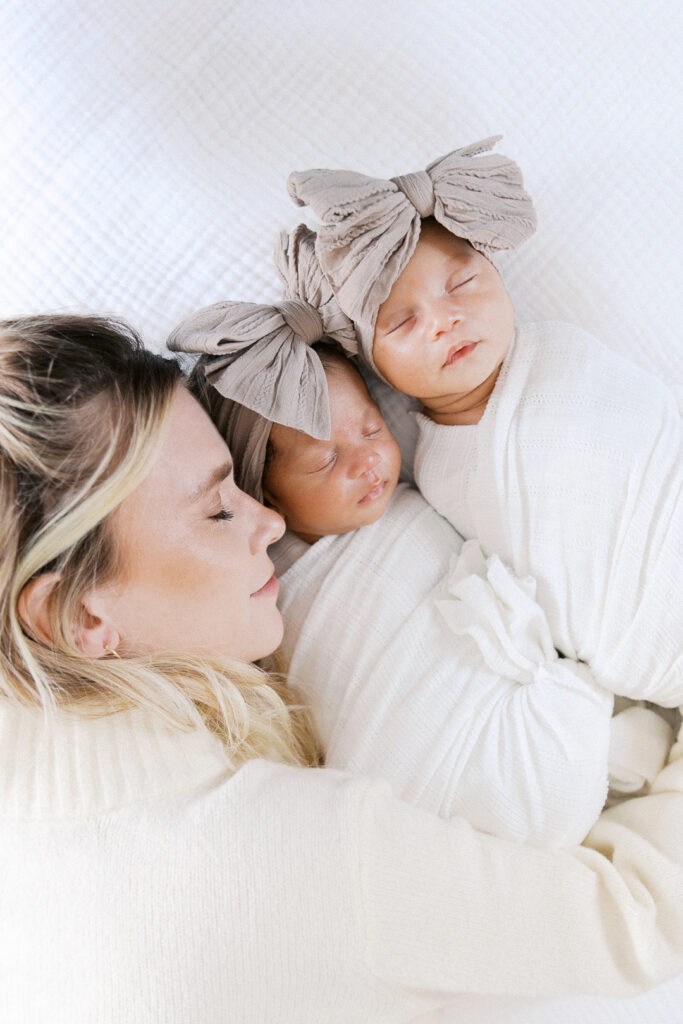 mom snuggling two sleeping twin baby girls