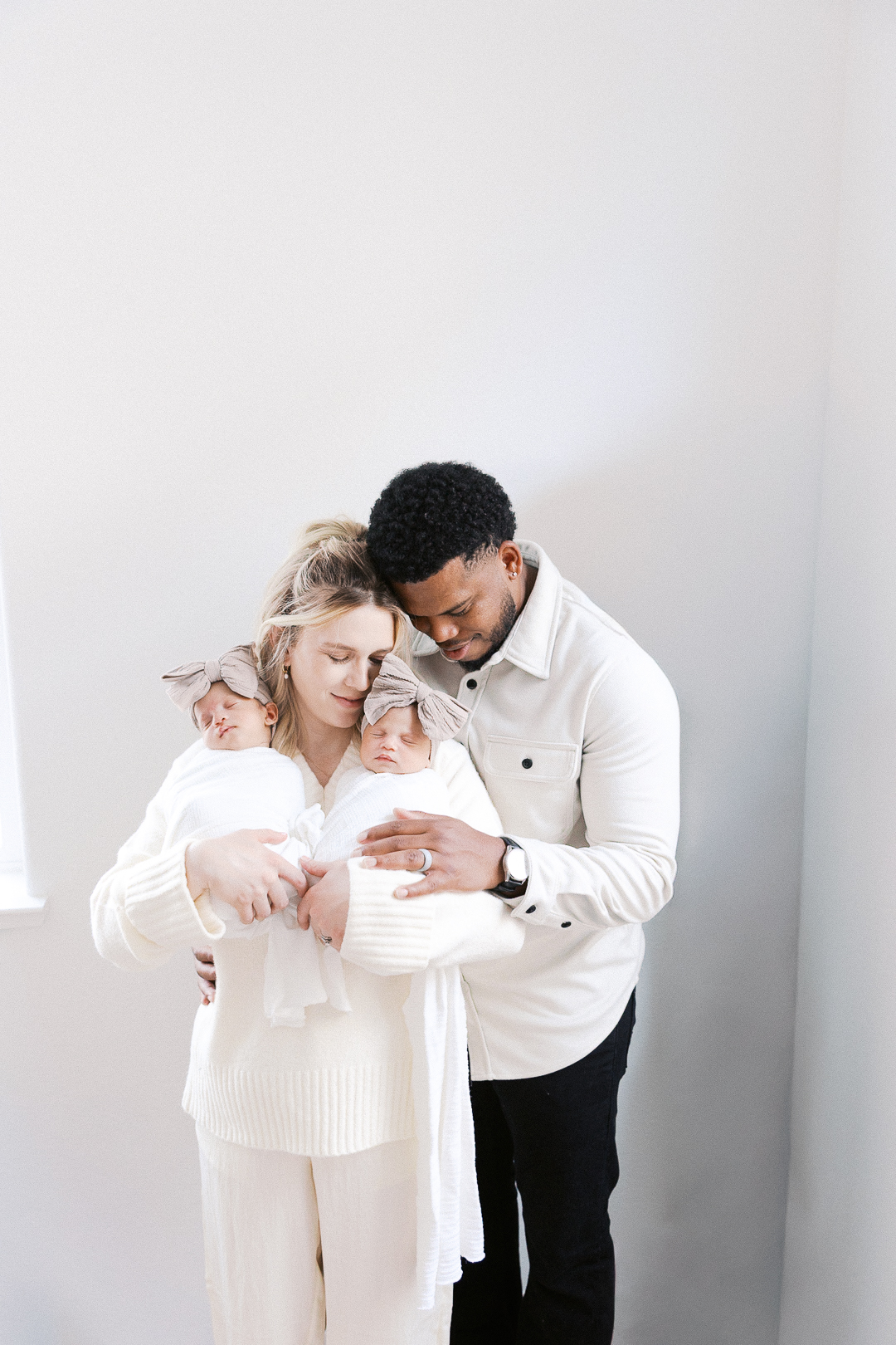 mom and dad embracing while holding twin baby girls