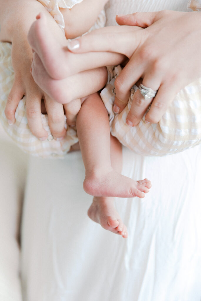 baby's bare feet and mom's hands