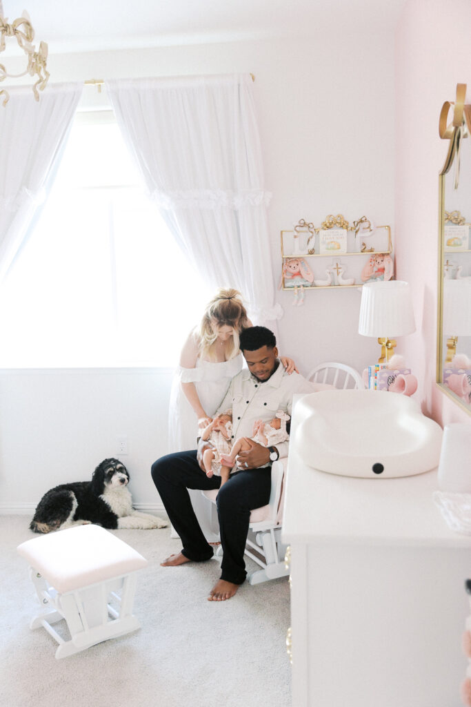 mom and dad sitting in nursery looking at the twin baby girls