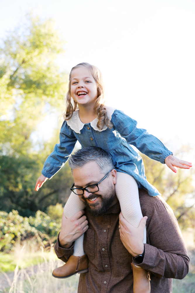 little girl sitting on her daddy's shoulders